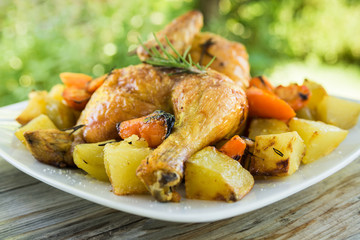 Piatto di pollo arrosto con contorno di patate e carote al forno