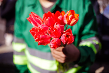 Man in uniform handing tulips to women on street