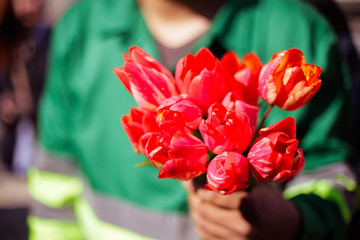 Man in uniform handing tulips to women on street