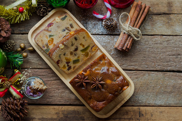 Homemade fruit cake on wood plate. Rum fruit cake with dried fruits made for Christmas celebration. Traditional homemade fruit cake so delicious, rich and moist. Christmas background with copy space.