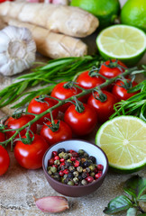 Food background with different ingredients on a marble background. Cherry tomatoes, rosemary, garlic, pepper, lime. Top view.