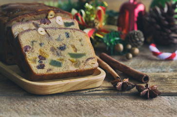 Homemade fruit cake on wood plate. Rum fruit cake with dried fruits made for Christmas celebration. Traditional homemade fruit cake so delicious, rich and moist. Christmas background with copy space.