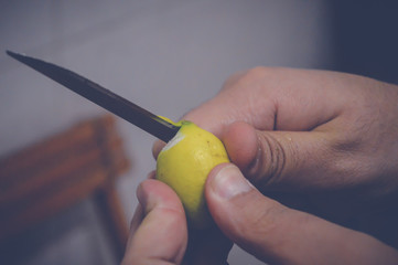 closeup of human cutting lemon on wooden table