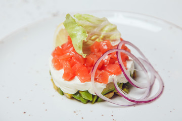 Salad with salmon, avocado and cheese decorated with lettuce leaves.