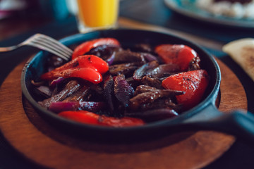 Mexican fajitos in a frying pan on a table.