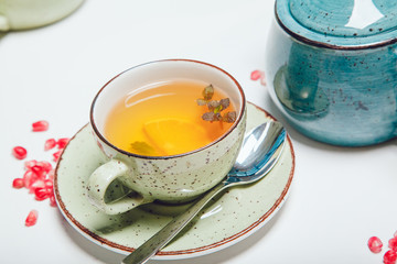 Tea in cup with leaf mint and lemon on white table.