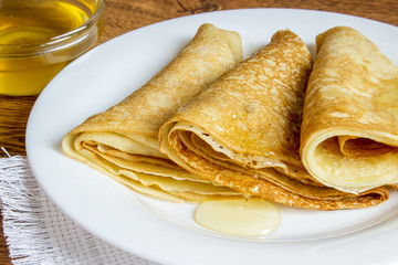 pancakes with honey syrup on a white plate. traditional crepe or pancake