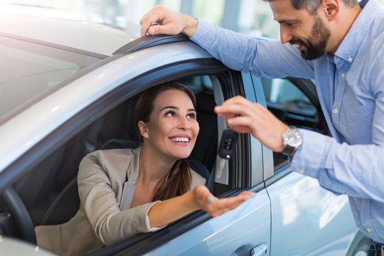Woman receiving keys from a car dealer
