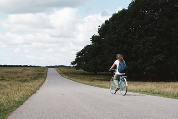 Obraz premium Smiling pretty young woman riding bike in a country road in the park
