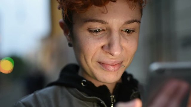 Portrait of young woman lesbian using smart phone, face illuminated by screen light &ndash; night life, intenret, communication concept