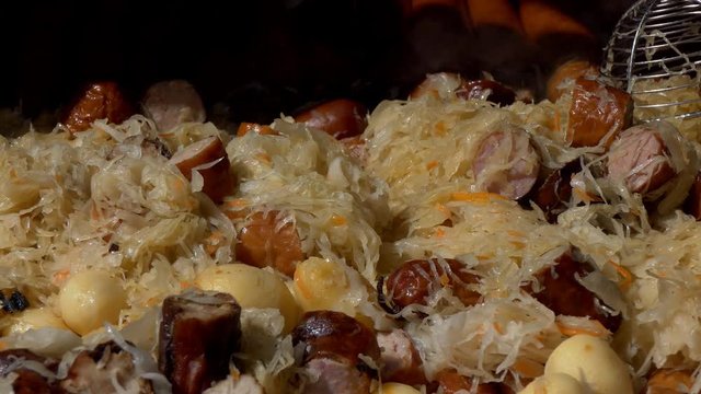 Traditional Eastern European cuisine. Sauerkraut, shredded cabbage, potatoes and meat based stew vapouring vaporing in a big frying pan.