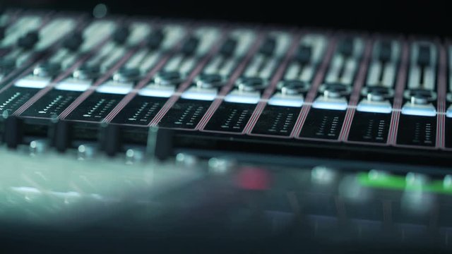 audio mixer in a studio, the automatic knobs moving up and down on console. Broadcast Tv Studio Production. Vision Switcher. Broadcast video mixer. Mixing board with automation. Close-up button. DOF