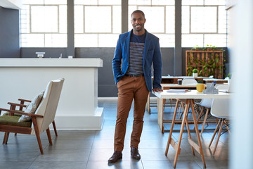 Smiling young African businessman standing confidently in a modern office