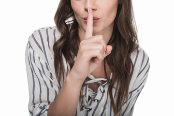 Naklejka premium Cropped shot of beautiful brunette girl gesturing for silence with finger on lips