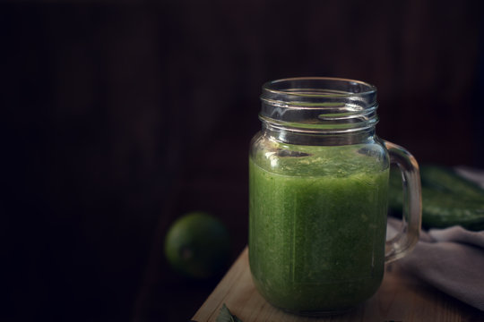 Healthy green smoothie on a wooden table. Dark background