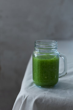 Fresh organic green smoothie with spinach, cucumber on a white tablecloth