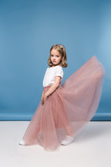 Beautiful little girl in pink skirt posing in studio and looking at camera