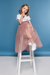 Cute pensive little girl sitting on ladder and looking away