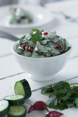 Cucumber salad with yogurt dressing on the white background