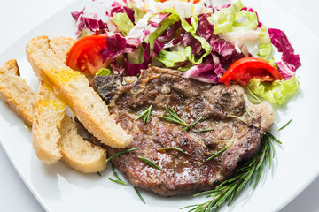 Bistecca di maiale arrosto con contorno di insalata e crostini 
