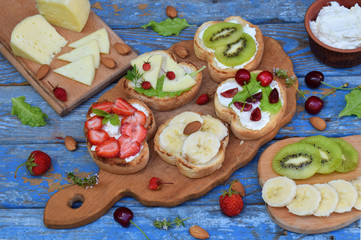 Set of assorted healthy wholewheat bread sandwiches with fruit, cheese and leafy green herbs on...