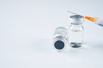 Medical ampoules, infusion and syringe with injection isolated on white background with copy space. Ampules with antibiotics closed with caps in a row. Syringe with needle lying on the vial with drug