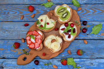 Set of assorted healthy wholewheat bread sandwiches with fruit, cheese and leafy green herbs on picnic wooden table. Ciabatta sandwich bar or buffet. Top view. Making lunch time snacks concept.