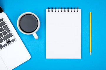 Modern designer office desk table with blank notebook page, laptop computer and cup of coffee