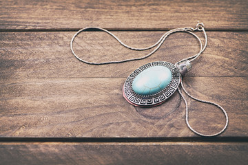 Pendant with stone on brown wooden table. Isolated.