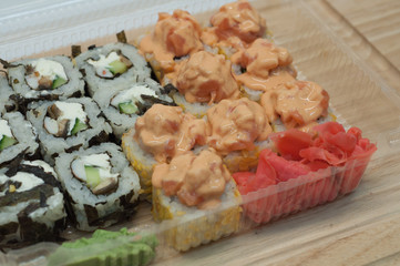 Японская еда роллы с имбирем и васаби в одноразовом контейнере на деревянном фоне