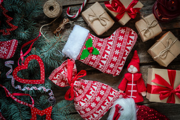 Christmas gifts in craft paper, gift bag in christmas pattern on wooden background, Christmas tree with red decor, top view