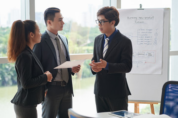 Group of creative young managers discussing new ideas at business training, panoramic window of spacious boardroom on background