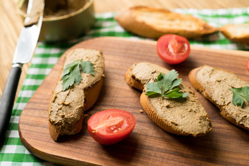 Liver pate on the bread on wooden tray.