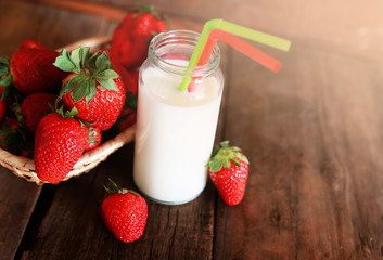 wooden table with strawberries and milk in a glass