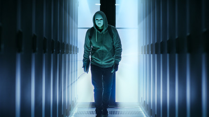 Masked Hacker Wearing Hoodies Walks in Through Data Center Corridor.