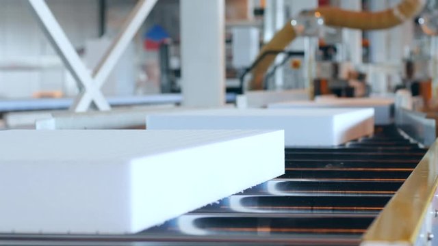 production equipment at industry, production of foam plastic, processing of styrofoam in factory, automated complexes manufacturing polyvinyl chloride foams, styrofoam on conveyor line,