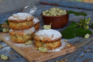 Homemade sweet muffins with white mulberry. Berry cupcakes on a wooden background.