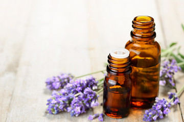 Lavender essential oil in the amber bottle, on the wooden table - obrazy, fototapety, plakaty