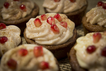 A close-up of a delicious curd-chocolate capkake, covered with a sweet cheese cream and decorated with pieces of juicy pomegranate