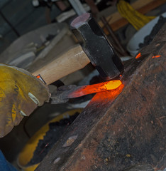 The bladesmith skillfully hammers red hot metal to shape it into a useful product
