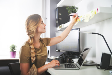 Woman working on computer at home office taking notes
