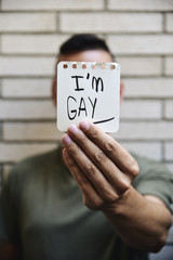 young man with a note with the text I am gay