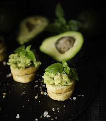Toasts with pasta from avakado or guacamole and spices on wooden table with fruits, selective focus, concept