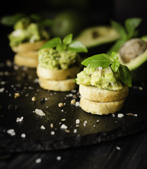 Toasts with pasta from avakado or guacamole and spices on wooden table with fruits, selective focus, concept