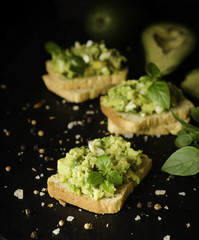 Toasts with pasta from avakado or guacamole and spices on wooden table with fruits, selective...