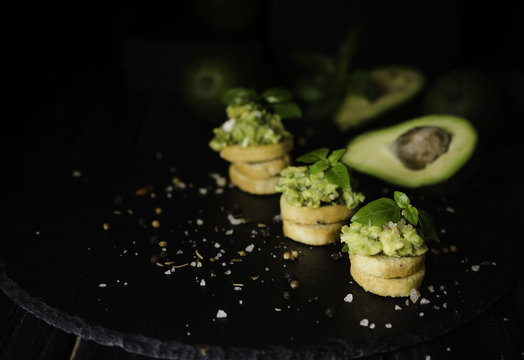 Toasts with pasta from avakado or guacamole and spices on wooden table with fruits, selective focus, concept