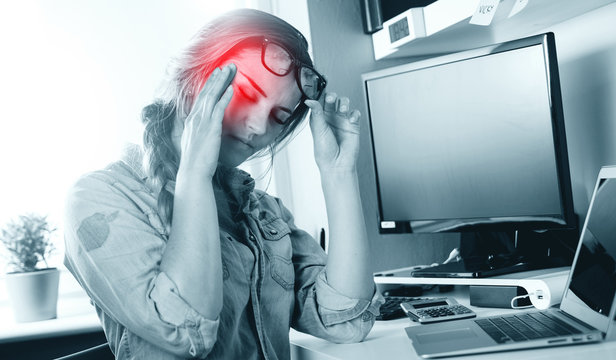 Woman in home office suffering from headache sitting at desk