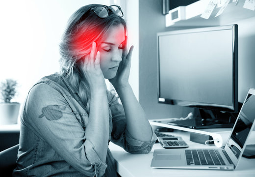 Woman in home office suffering from headache sitting at desk