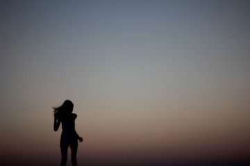 Fototapeta premium Silhouettes of a girl running on a gradient of a colorful sunset