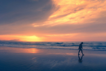 Fototapeta premium lonely person walking on beach at sunset